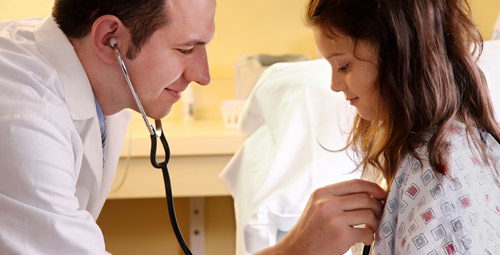 A doctor using a stethoscope of a young girl